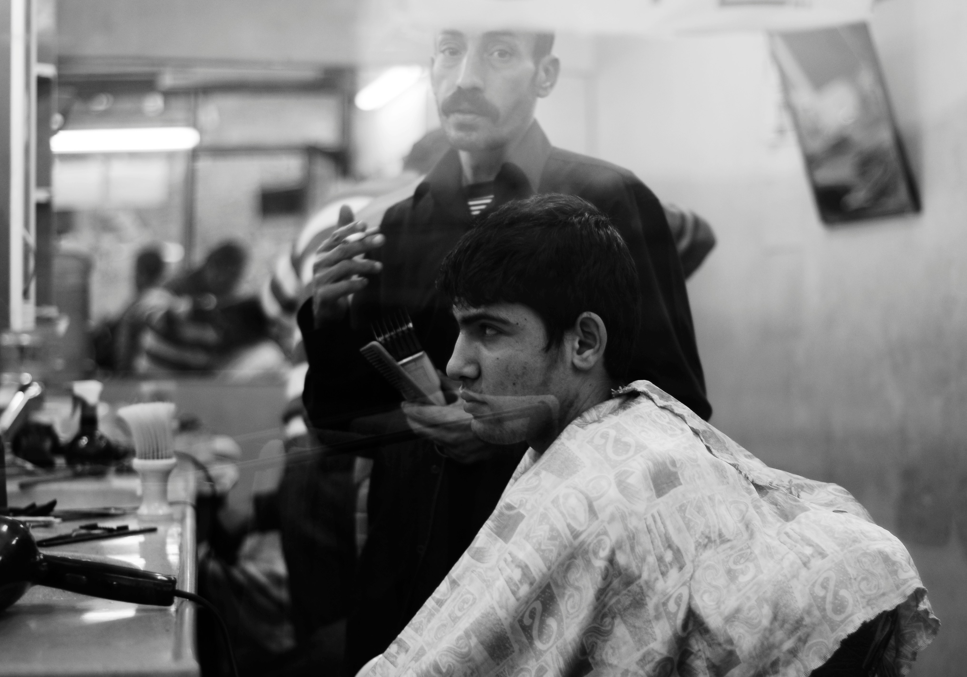 grayscale photo of man inside barber shop